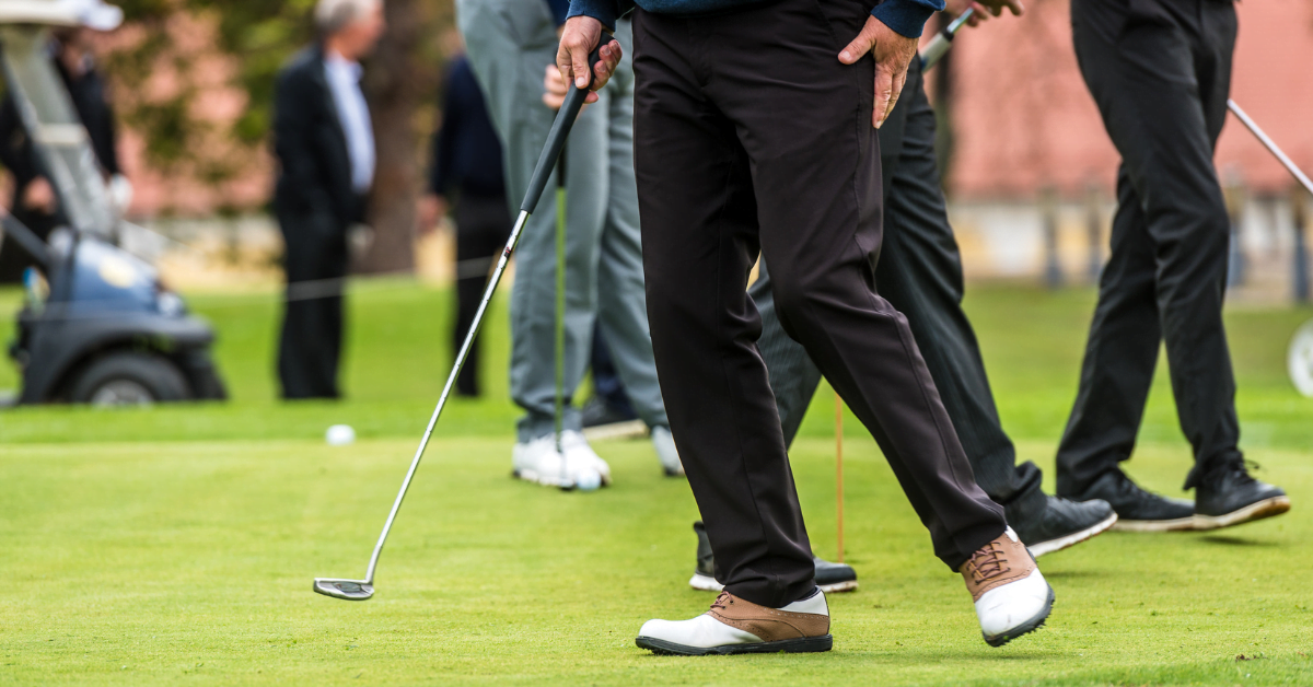 Many golfers practicing on a putting green.