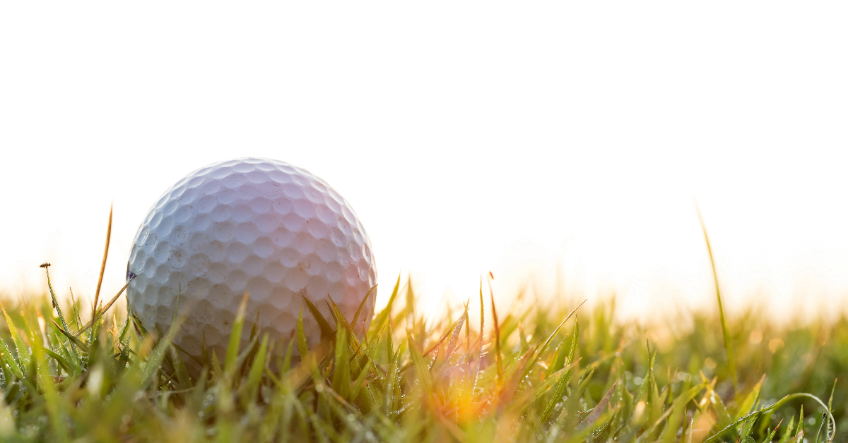 Golf ball with sun reflecting off of the grass.